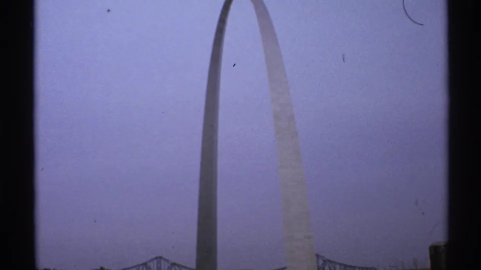 1972 Saint Louis frame showing the Gateway Arch from a low angle, rendered in soft 8mm color with dark edge framing.
