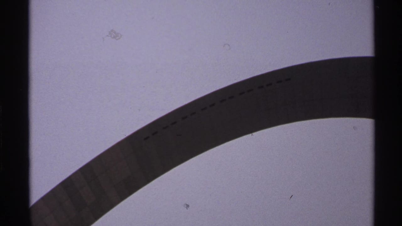 Saint Louis Gateway Arch appears from a low angle in 1970s 8mm home-movie footage, with grain, dust, and dark frame borders.