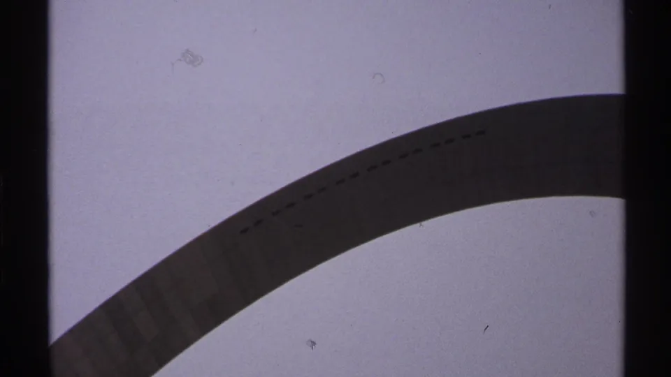 Saint Louis Gateway Arch appears from a low angle in 1970s 8mm home-movie footage, with grain, dust, and dark frame borders.