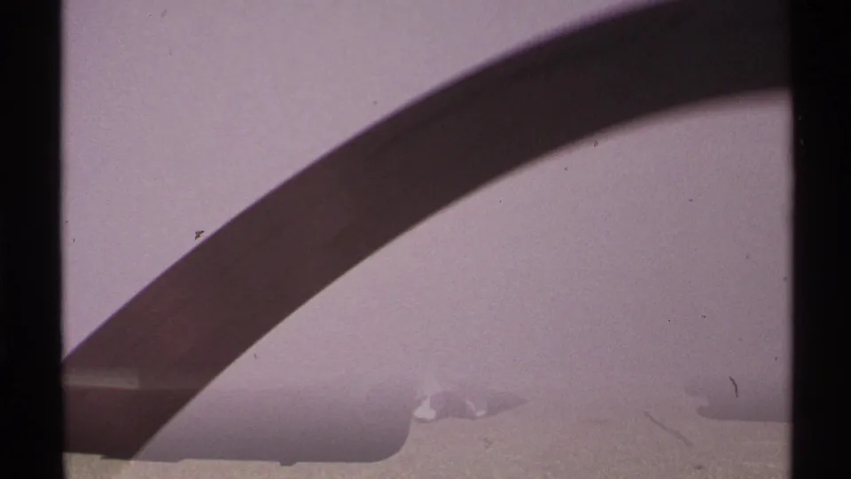 The Saint Louis Gateway Arch curve descends toward the lower frame, with soft exposure, grain, and faint foreground structure visible.