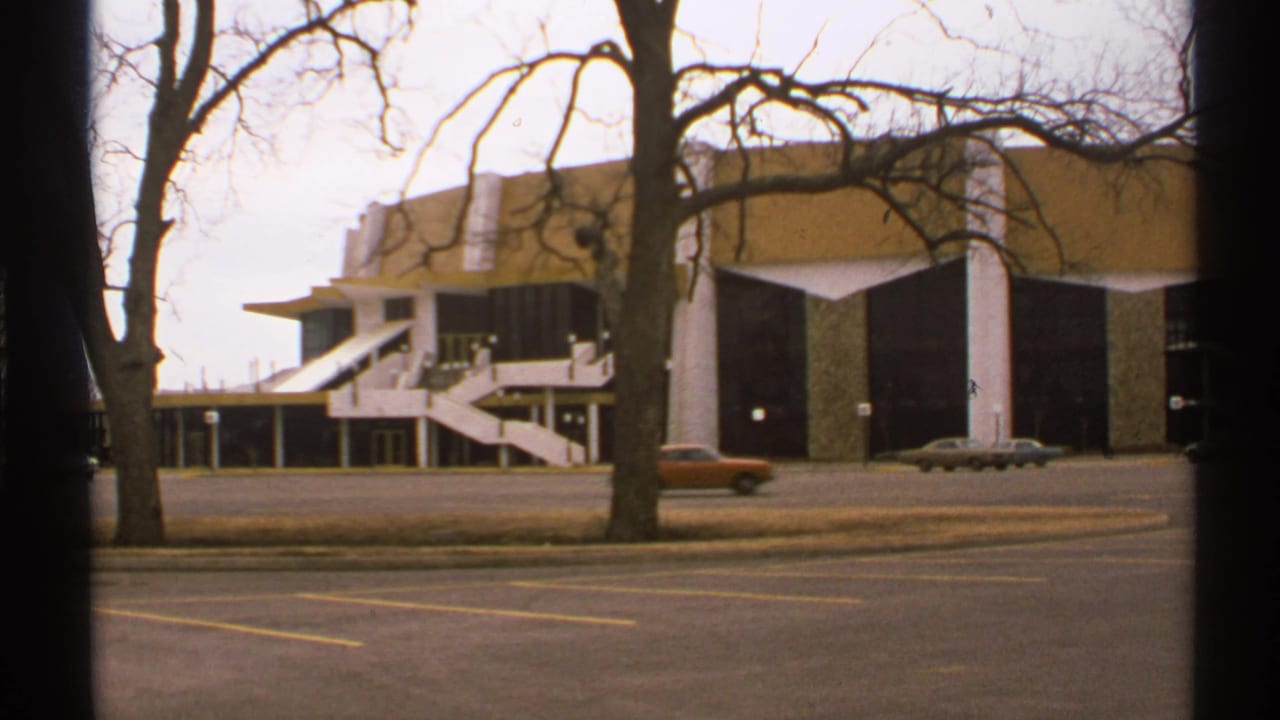 1972 Tulsa street view of a large modernist building with exterior stairs, leafless trees, and period cars in front.