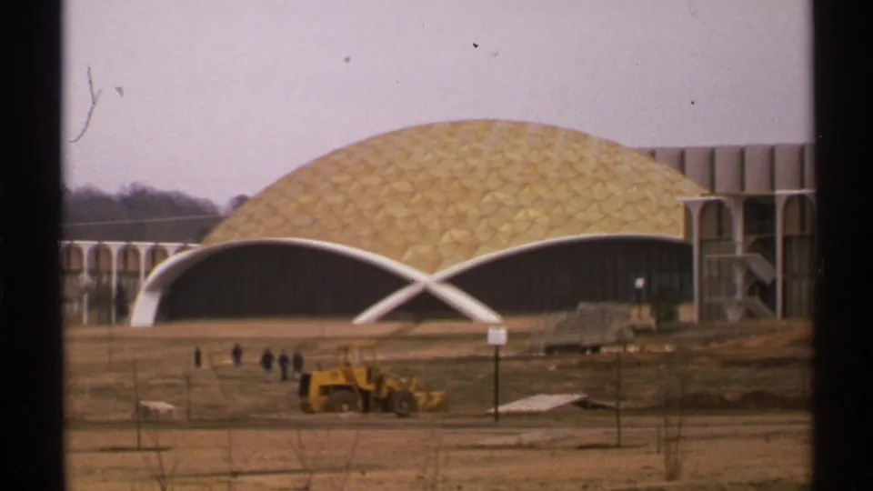 Howard Auditorium at Oral Roberts University in 1972, showing the golden dome, white arches, distant workers, and yellow bulldozer.