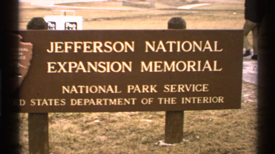 Close 8mm frame of the brown Jefferson National Expansion Memorial sign with National Park Service and Department of the Interior wording visible.