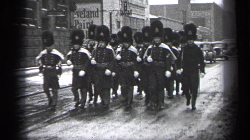 1937 Cleveland street view with uniformed men in bearskin-style hats marching toward the camera in formation.