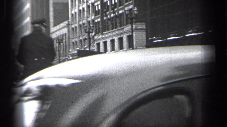 Mounted police officer in a 1937 Cleveland street scene, partly obscured by a close passing automobile.
