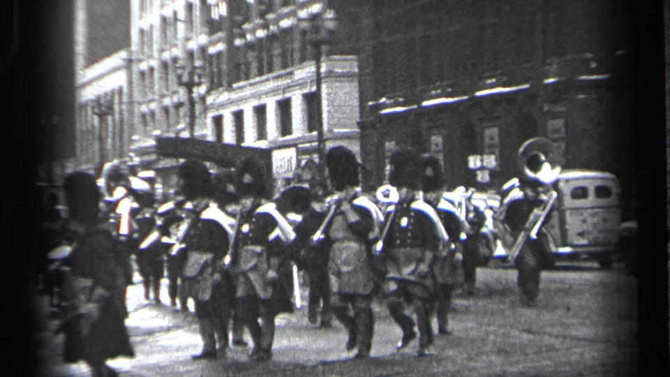 Uniformed musicians in a 1937 Cleveland street parade carry drums and brass instruments while pedestrians watch from the sidewalk.