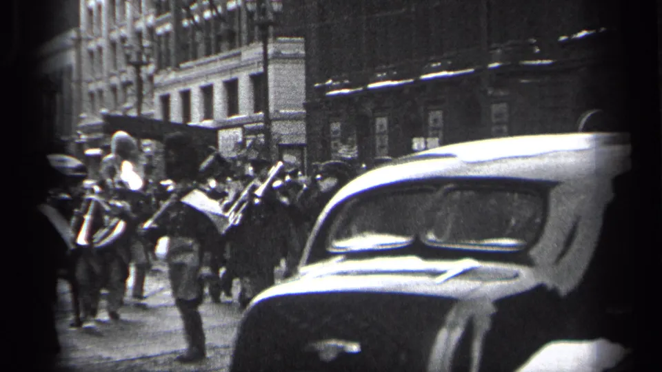Cleveland 1937 parade view with band members and brass instruments partly obscured by a passing period automobile.