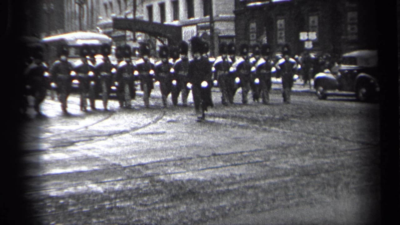 A small pedestrian runs in front of uniformed marchers on a wet urban street.