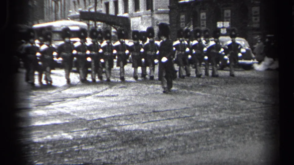 1937 Cleveland home-movie frame showing a closer view of uniformed marchers in formation on a wet city street.