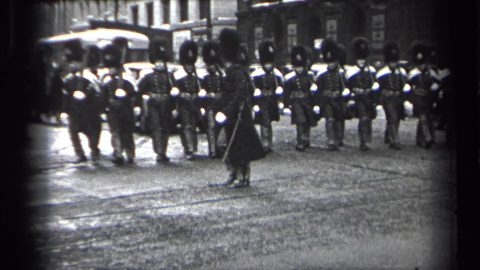 Uniformed men in ceremonial dress appear on a Cleveland street, with one figure in front and early automobiles visible in the background.