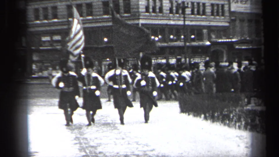 1937 Cleveland footage shows uniformed men carrying flags, including an American flag, marching away through a downtown streetscape.