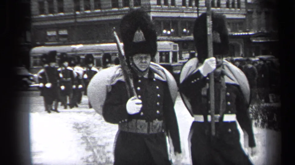 In the supplied 1937 Cleveland footage, soldiers in formal uniforms and tall hats march past the camera with rifles and white gloves.
