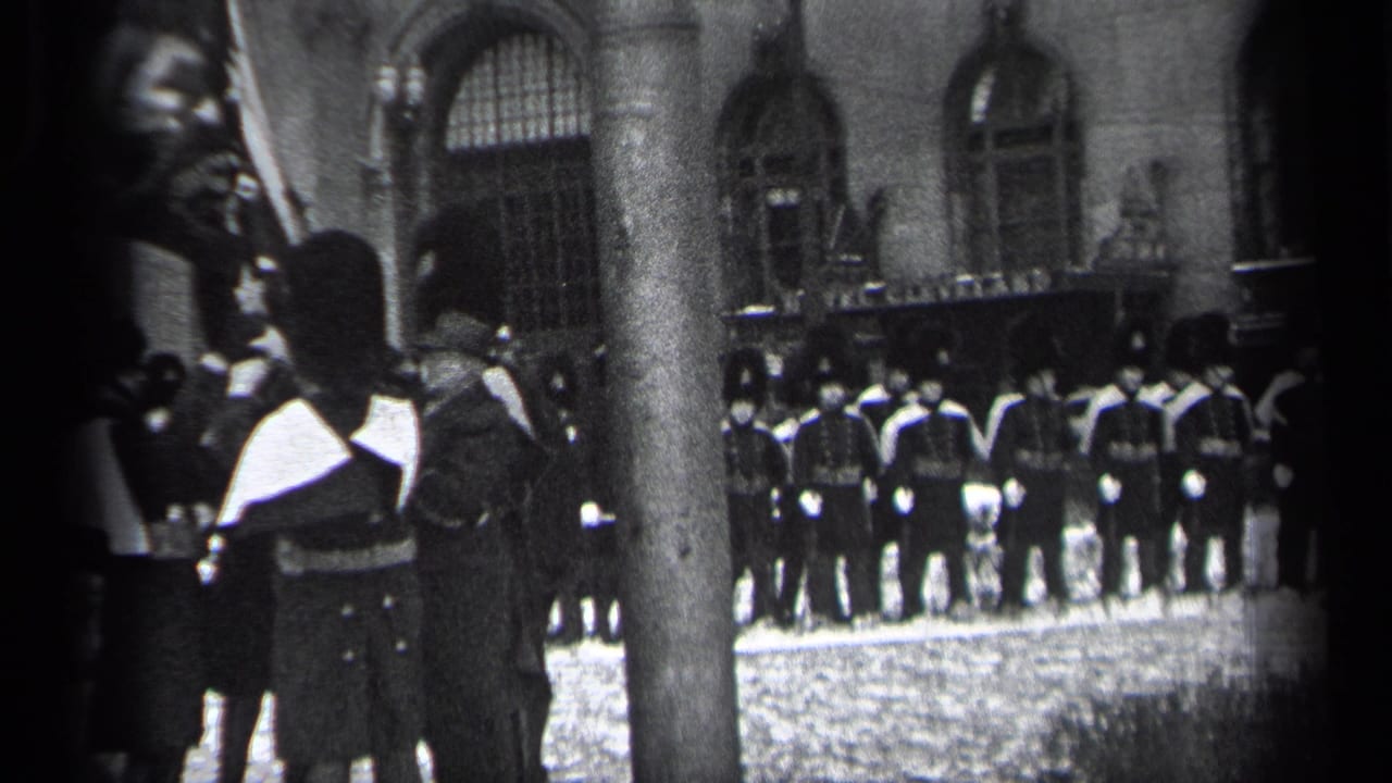 Uniformed personnel stand outside an arched building with a flag or standard nearby.