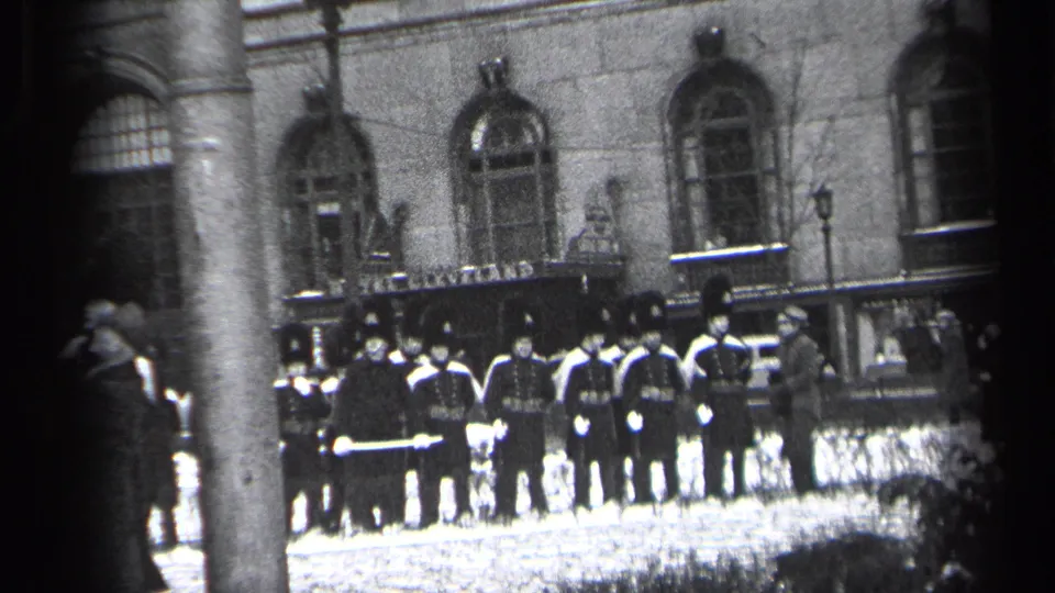 A slightly wider 1937 Cleveland frame shows the military formation outside the stone building, with a pole cutting through the foreground.