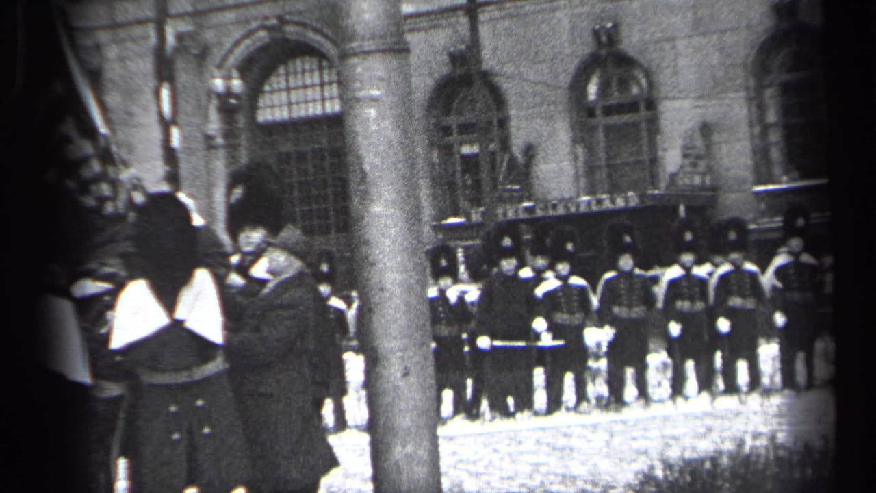 Uniformed guards stand near a stone building while a tree trunk partly blocks the view.