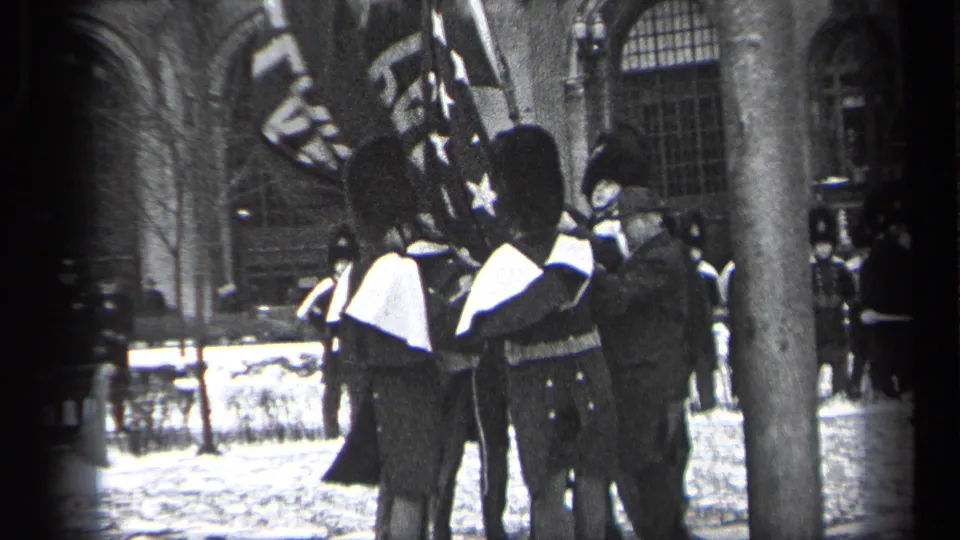 1937 Cleveland home-movie frame of ceremonial guards grouped with flags outside a stone building, with spectators nearby.