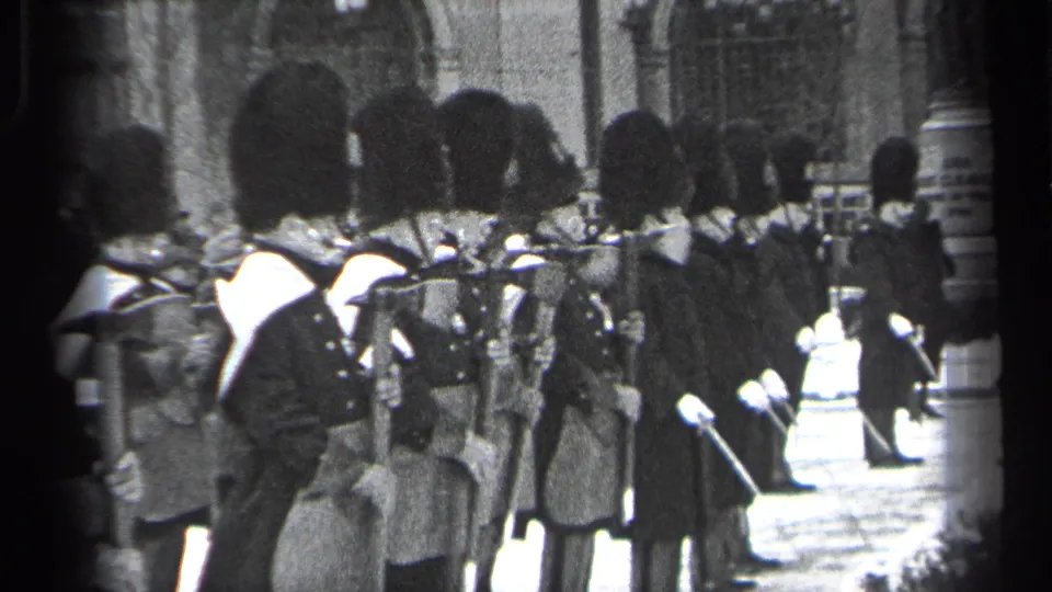 1937 Cleveland home-movie frame showing ceremonial guards in tall hats standing with rifles near snow-covered ground and railings.