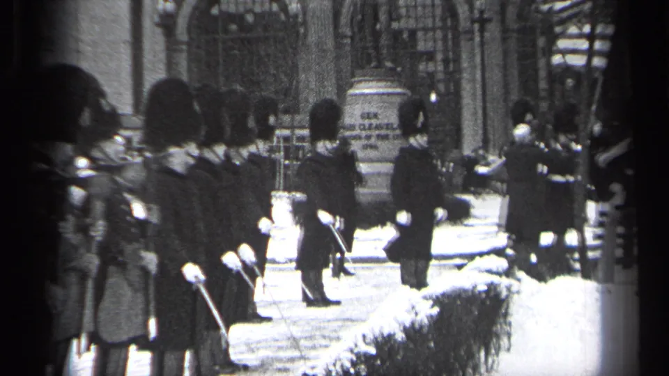 1937 Cleveland frame showing guards in ceremonial uniforms beside a flag, with snow on the ground and hedges nearby.