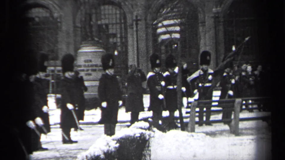 1937 Cleveland home-movie frame with ceremonial guards, a flag, and spectators watching from behind a wooden railing.