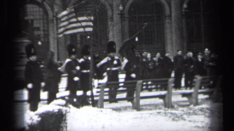 1937 Cleveland frame showing flag-bearing ceremonial guards with spectators gathered behind a rail in a snow-covered setting.