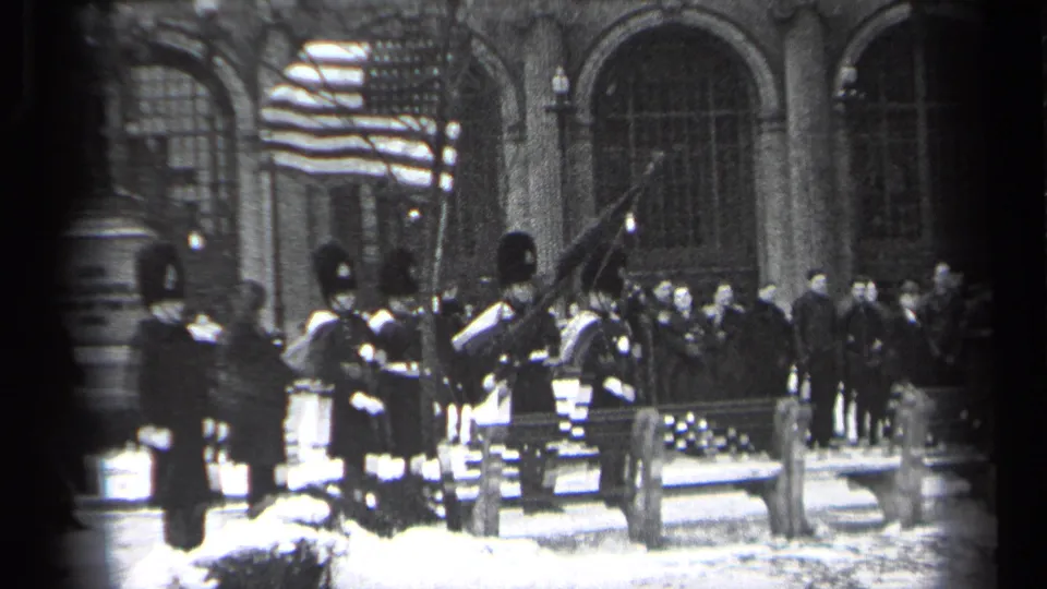 Uniformed guards and onlookers appear in a snowy Cleveland ceremony as the American flag is held or raised nearby.