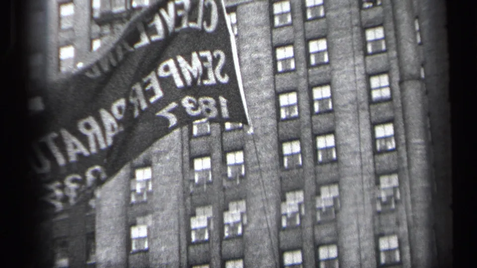 The frame centers on a banner reading Cleveland Semper Paratus 1837 with a high-rise building facade behind it.