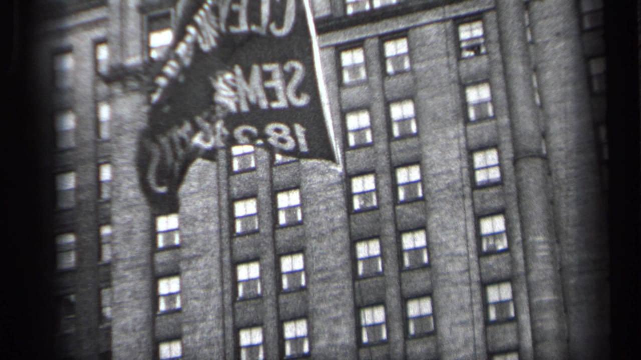 Flag with reversed lettering in front of a tall windowed building.