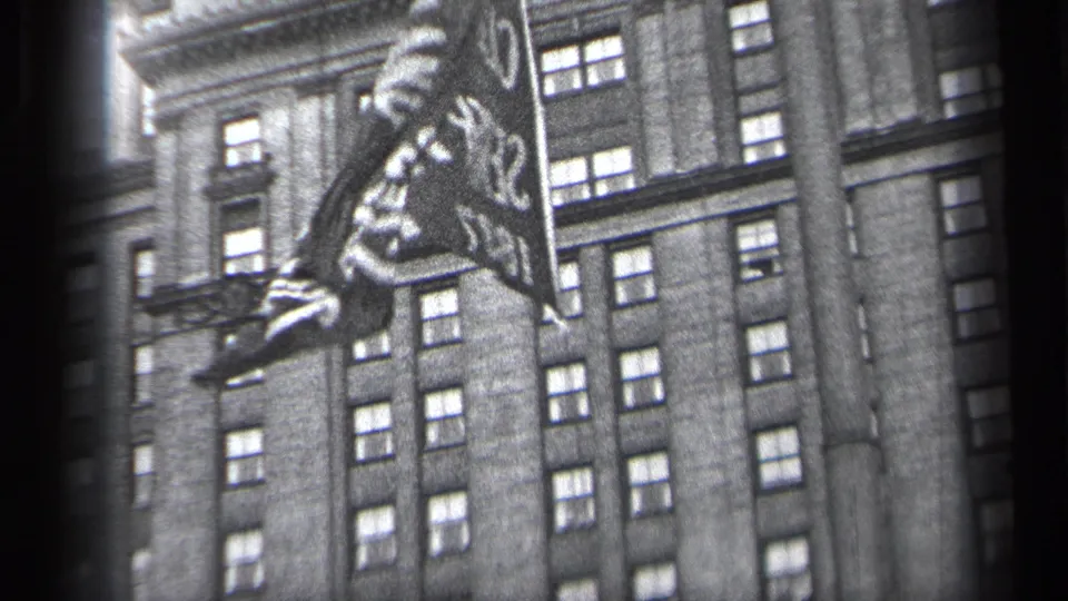 1937 Cleveland frame with a cropped flag edge and lettering moving in front of a tall windowed building.