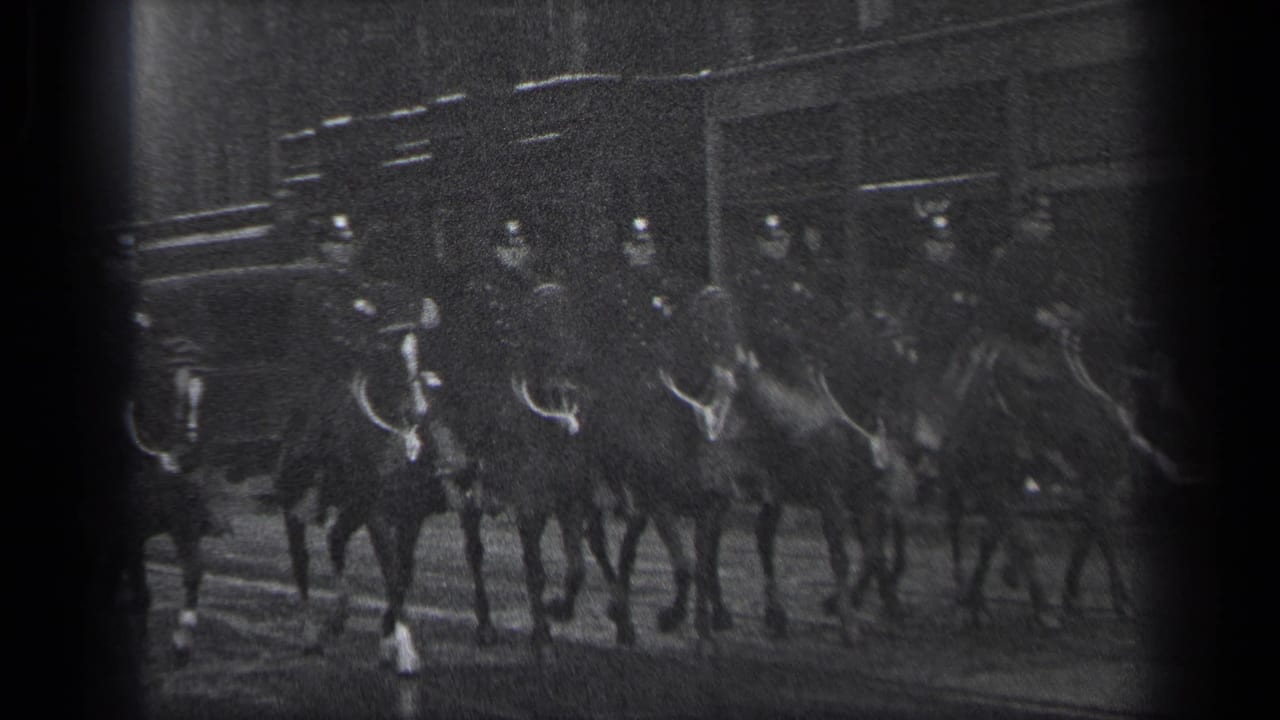 In 1937 Cleveland, mounted police officers in dark uniforms ride horses past urban buildings in grainy 8mm footage.