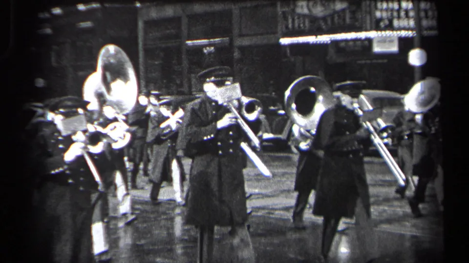 1937 Cleveland street scene with uniformed band members playing brass instruments under night lighting on wet pavement.