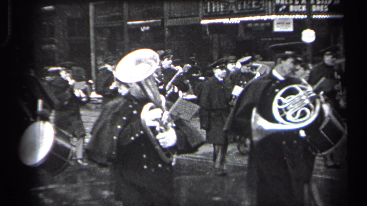 1937 Cleveland street scene with uniformed band members playing brass instruments and drum near storefront lights.