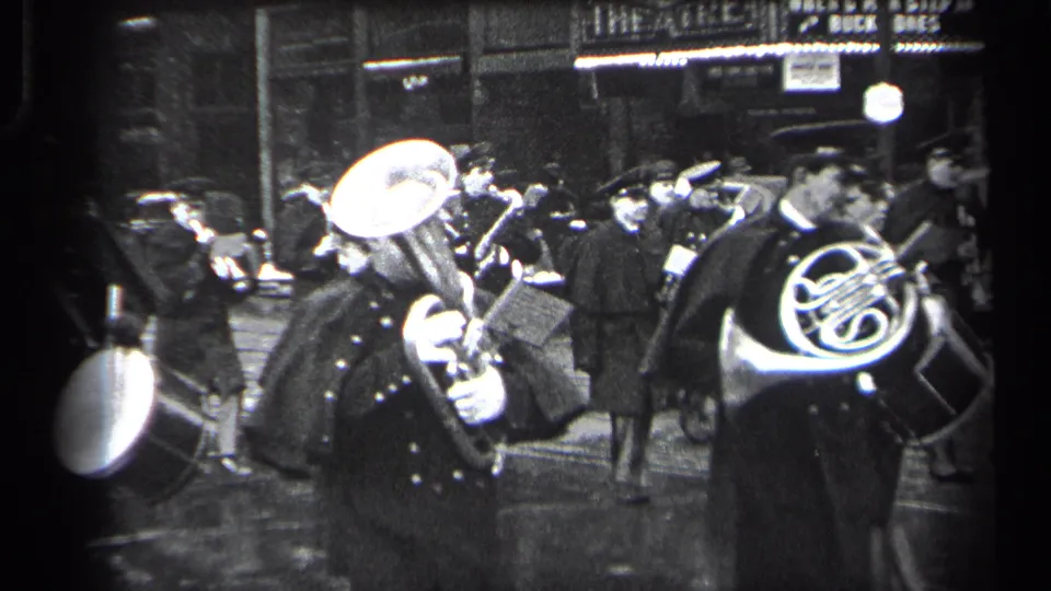 1937 Cleveland street scene with uniformed band members playing brass instruments and drum near storefront lights.