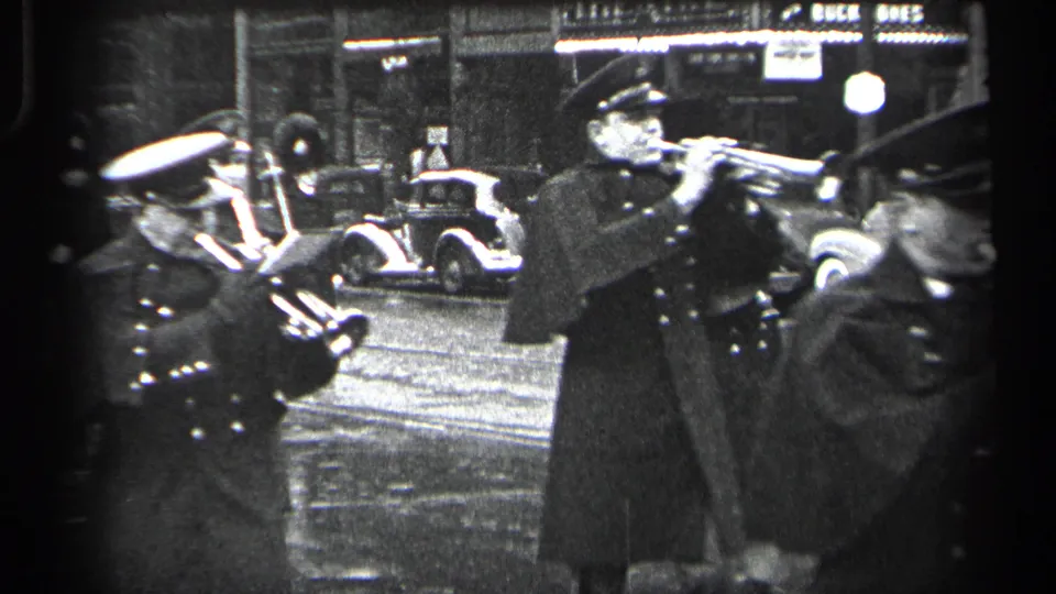 A uniformed trumpet player is seen in profile during a 1937 Cleveland street band performance at night.