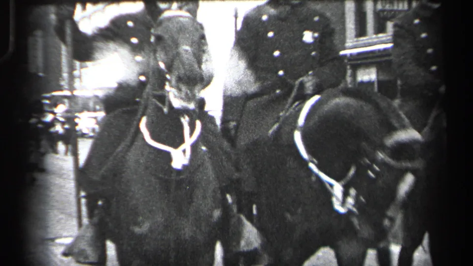 Close black-and-white frame of police horses and mounted officers passing near the lens during the Cleveland parade.