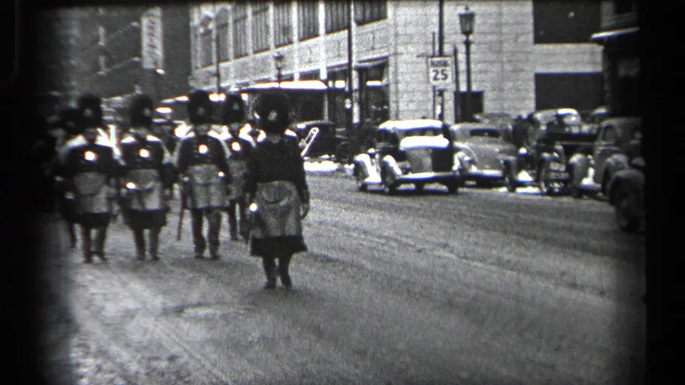 A closer 1937 Cleveland street view shows uniformed marchers with rifles, kilts, and white belts passing parked automobiles and storefronts.