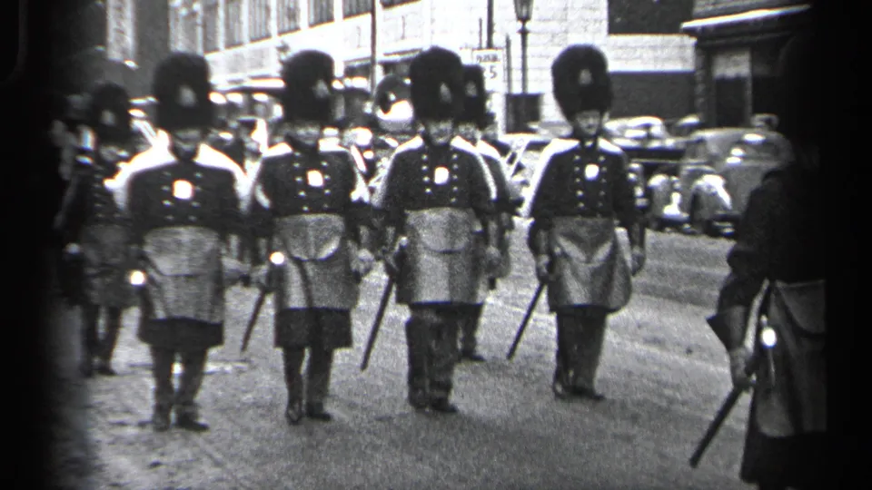 Three men in formal parade dress, including tall hats and kilt-like garments, march close to the camera in Cleveland, Ohio, 1937.