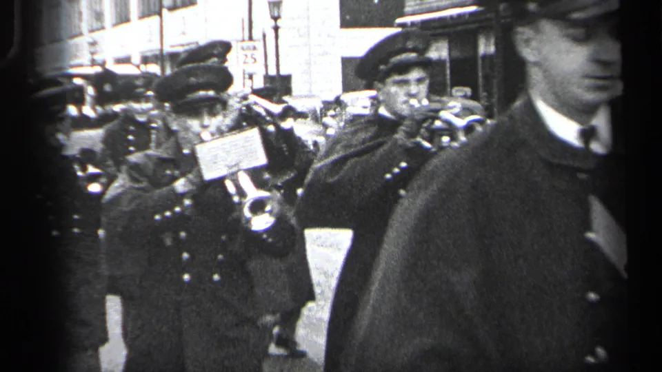 1937 Cleveland street parade view with uniformed musicians in dark coats and peaked caps carrying trumpets among other marchers.