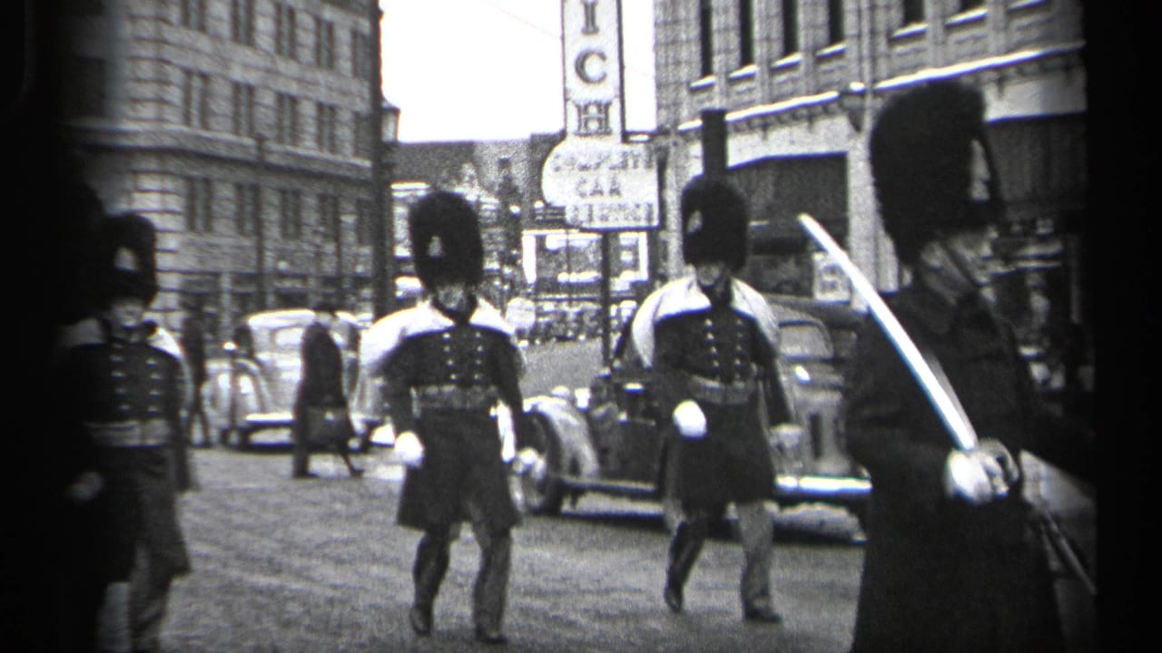 Ceremonial guards pass a parked car and storefront signs on an urban street.