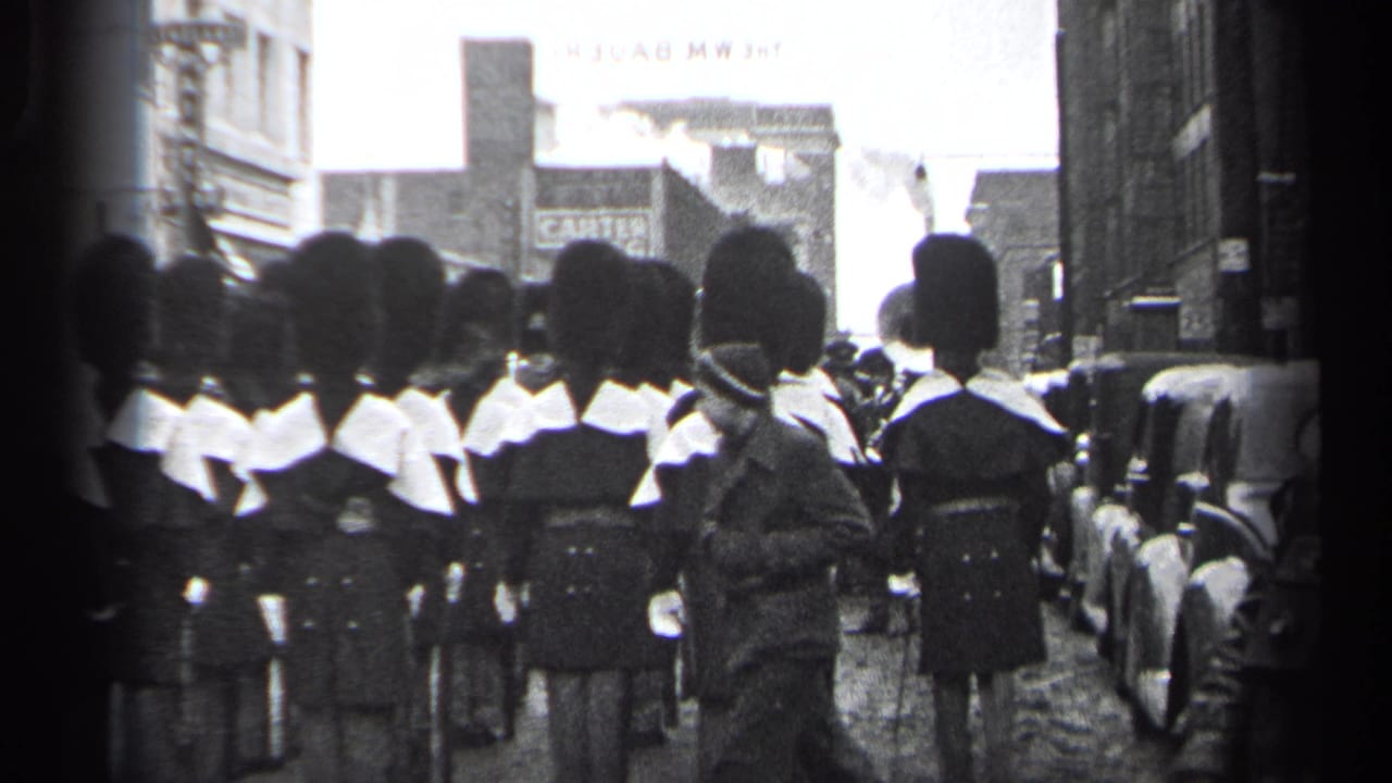 1937 Cleveland parade view of uniformed marchers in tall dark hats and white collars moving away from the camera on a city street.