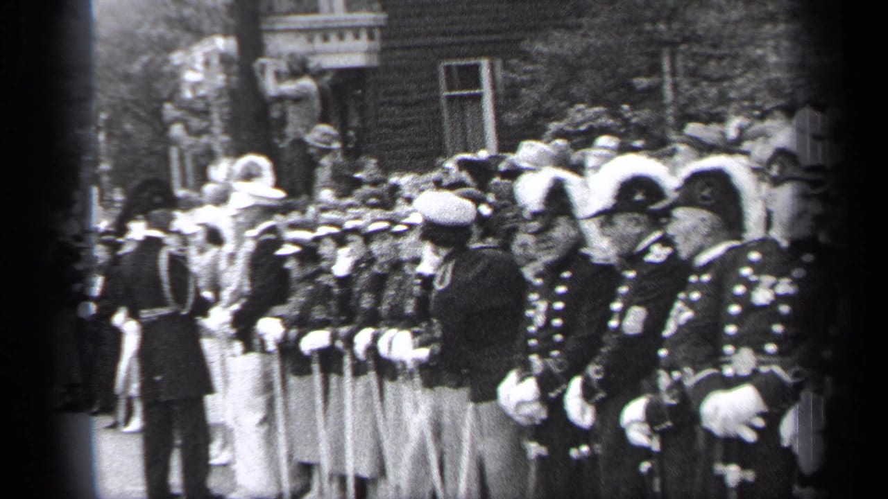 Uniformed men line the street while a crowd watches behind them.