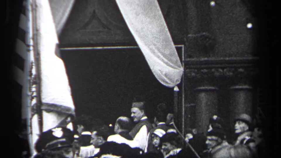 1937 Cleveland public-event frame showing a crowd beneath draped fabric, with a large flag and formal clothing visible.