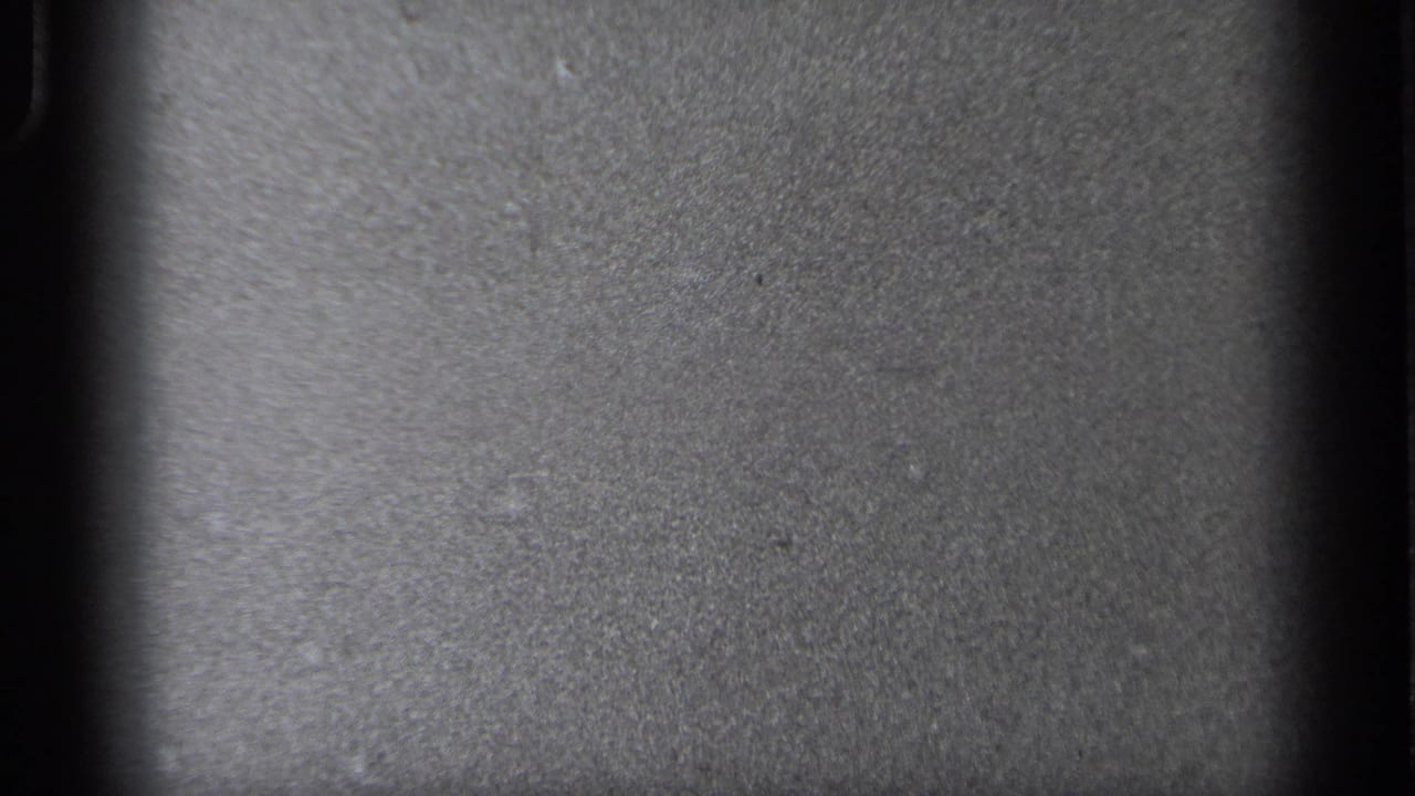 Mostly blank dark and gray film frame with visible grain.
