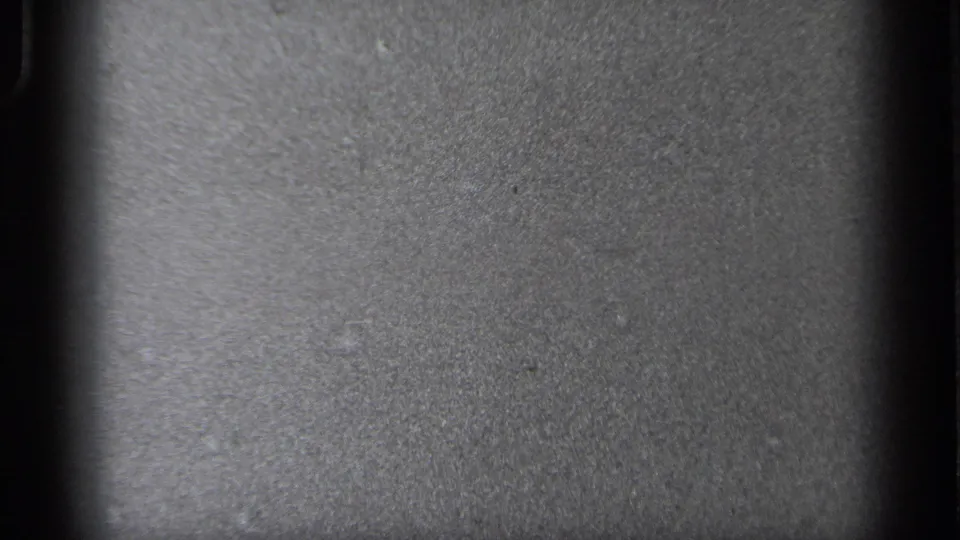 A transitional or underexposed 8mm frame showing gray film texture and dark vertical frame-edge areas rather than a clear street scene.
