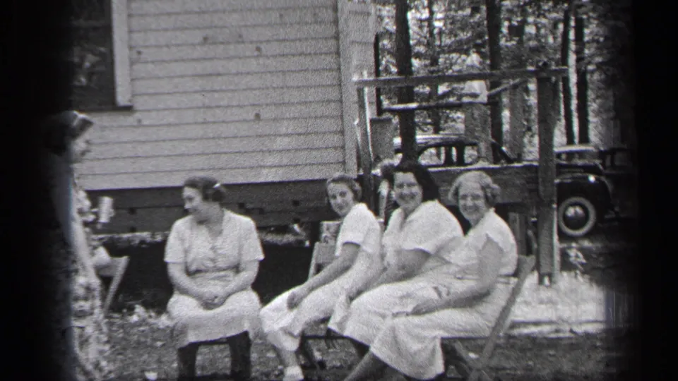 Four women sit in a yard beside a wooden porch in Cleveland, Ohio, in 1937 home-movie footage.