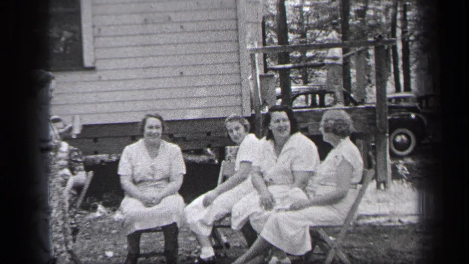 A group of women converse outdoors beside a wood-sided house in Cleveland, Ohio, according to the clip metadata.
