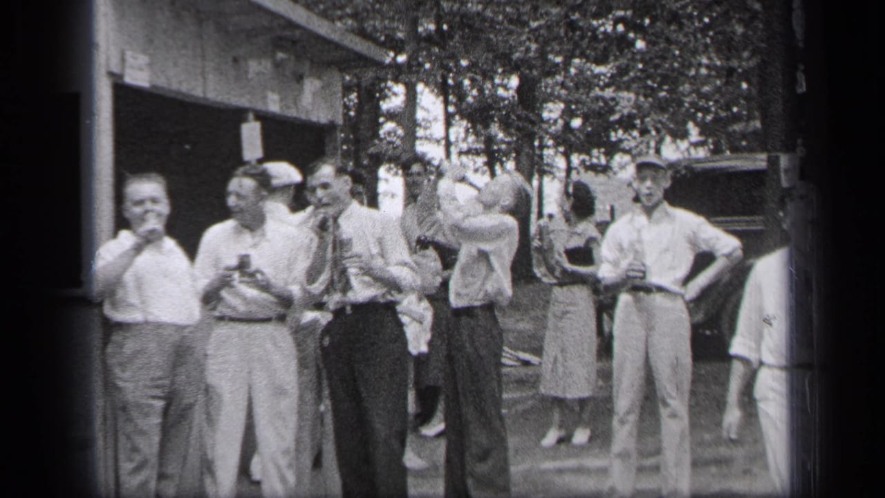 Several men smile and hold drinks while another raises a glass.