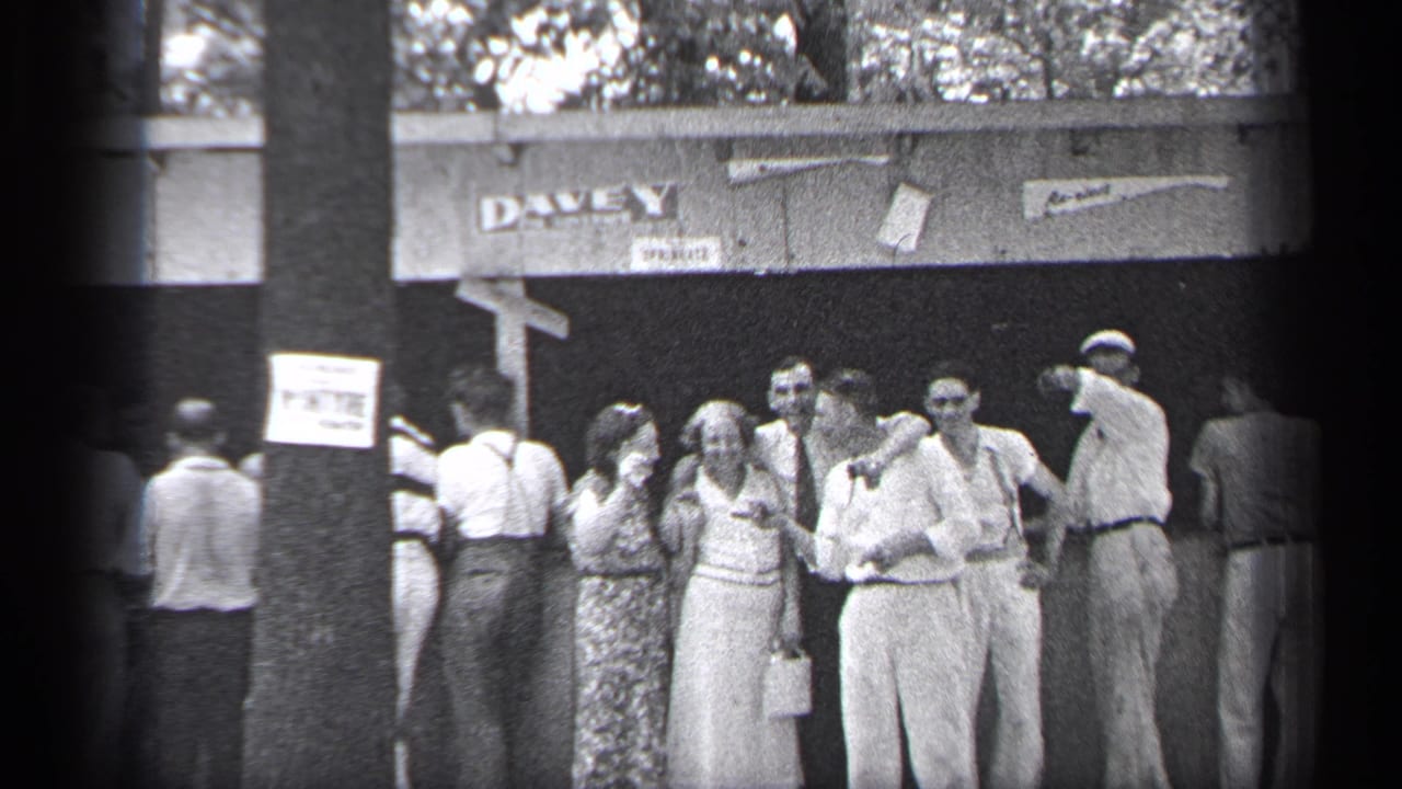 Group of adults continues greeting near the entrance as a man raises an arm at right.