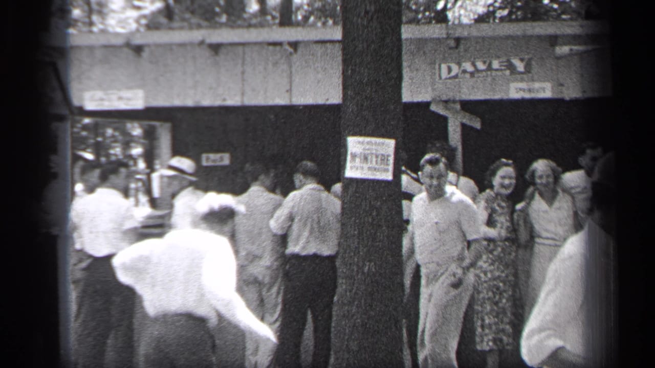 Sidewalk crowd near a tree and DAVEY sign, with several people facing the camera.
