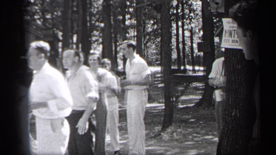 Adult men gather in a wooded Cleveland park in 1937, with a posted sign and casual summer clothing visible.