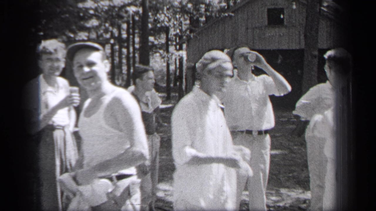 Several adults stand outdoors, with one man holding a can near his face.